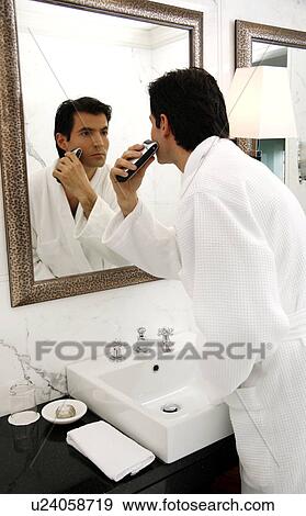 Stock Photo - Man shaving in the bathroom mirror. Fotosearch