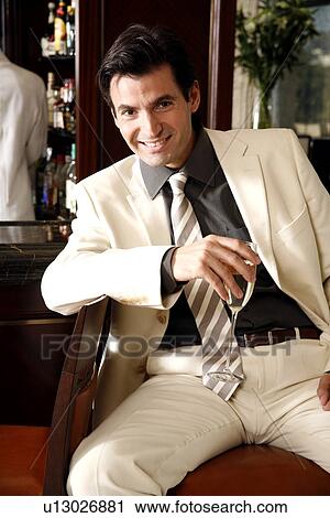 Stock Image - Man sitting at a bar drinking champagne. Fotosearch