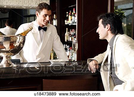 Stock Photo - Man sitting at a bar talking to the bartender. Fotosearch