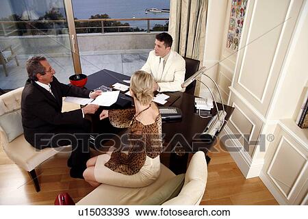 Stock Image - Three business people working in a hotel room. Fotosearch