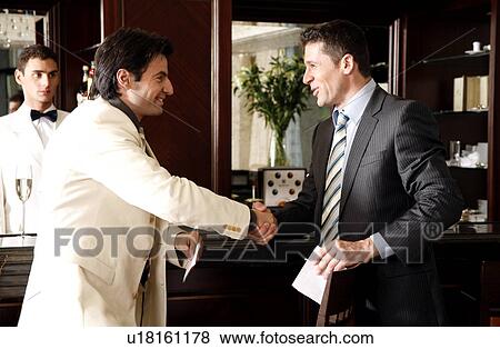 Stock Photo - Two men at a bar shaking hands. Fotosearch