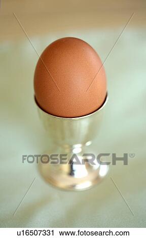 Stock Image - Boiled egg in a silver egg holder. Fotosearch