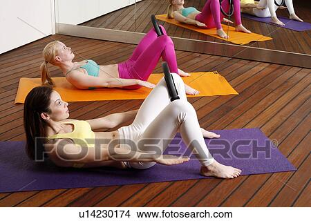 Picture - Two young women performing a pilates exercise. Fotosearch