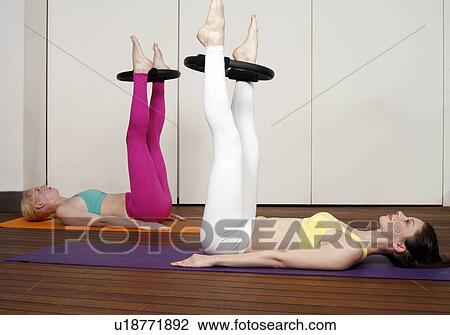 Stock Image - Two young women performing a pilates exercise. Fotosearch