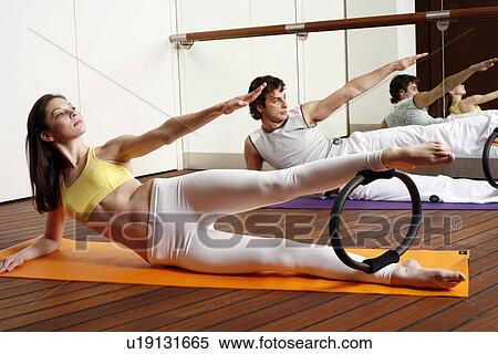 Stock Photography - Young man and woman performing a pilates exercise. Fotosearch
