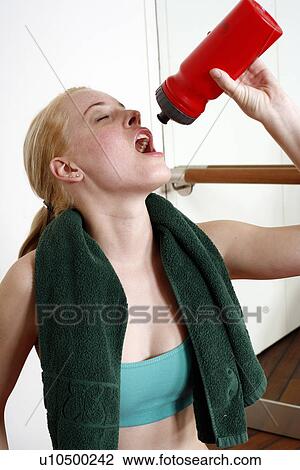 Stock Image - Young woman drinking water during an exercise session. Fotosearch
