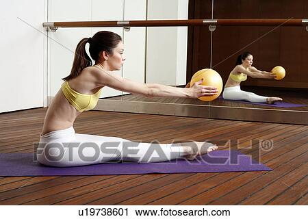 Young woman performing a pilates stretch with a ball View Large Photo Image Stock Image - Young woman performing a pilates stretch with a ball. Fotosearch