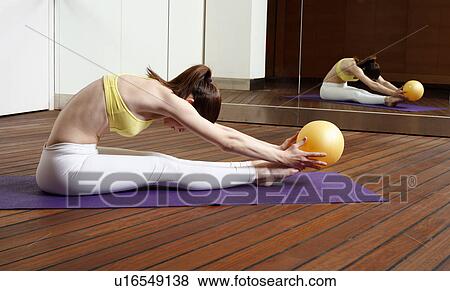 Stock Photo - Young woman performing a pilates stretch with a ball. Fotosearch
