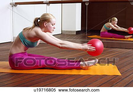 Stock Photography - Young woman performing a pilates stretch with a ball. Fotosearch