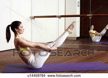 Picture - Young woman performing a pilates stretch. Fotosearch