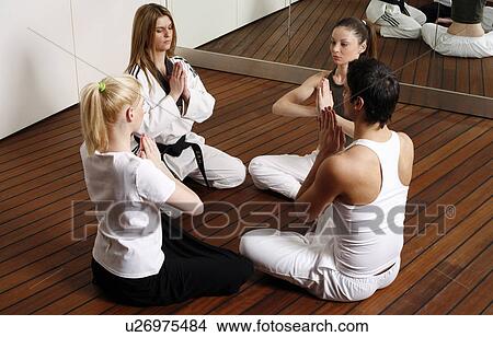 Picture - Participants in a fitness class meditating. Fotosearch