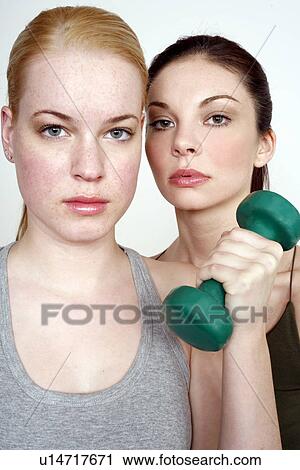 Stock Image - Two young women with dumbbell. Fotosearch