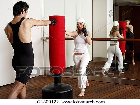 Young man and woman hitting the punching bag View Large Photo Image Stock Image - Young man and woman hitting the punching bag. Fotosearch