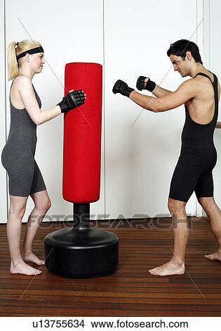 Picture - Young man and woman practicing with a punching bag. Fotosearch