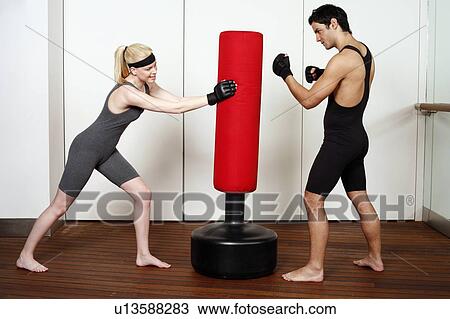 Young man and woman practicing with a punching bag View Large Photo Image Stock Image - Young man and woman practicing with a punching bag. Fotosearch