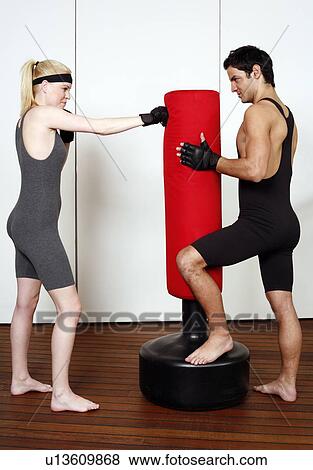 Young man and woman practicing with a punching bag View Large Photo Image Stock Photo - Young man and woman practicing with a punching bag. Fotosearch