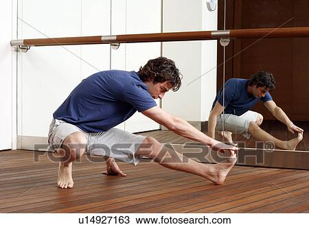 Stock Image - Young man stretching in gym. Fotosearch