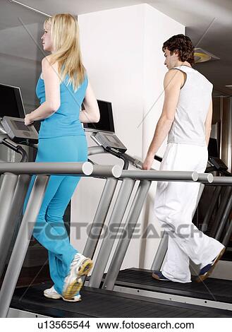 Young woman and man on treadmill View Large Photo Image Picture - Young woman and man on treadmill. Fotosearch