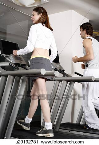 Stock Image - Young woman and man on treadmill. Fotosearch