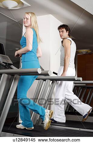Stock Photography - Young woman and man on treadmill. Fotosearch
