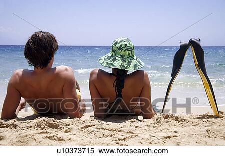Stock Photography - A couple with flippers on the beach. Fotosearch