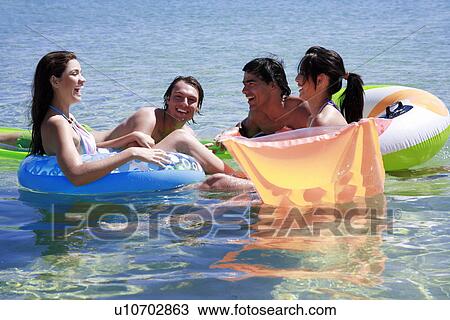 Stock Image - Group of friends playing in the water. Fotosearch