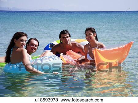 Stock Photo - Group of friends playing in the water. Fotosearch