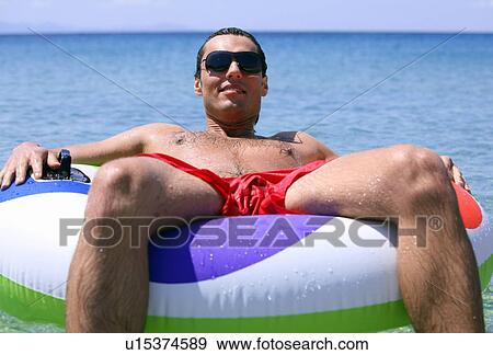 Man in the water on inflatable life ring View Large Photo Image Stock Photo - Man in the water on inflatable life ring. Fotosearch