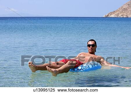 Man in the water on inflatable life ring View Large Photo Image Stock Photography - Man in the water on inflatable life ring. Fotosearch