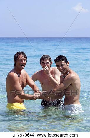 Picture - Three young men playing in the water. Fotosearch