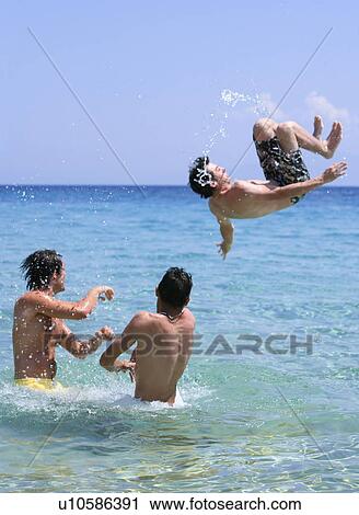 Three young men playing in the water View Large Photo Image Stock Image - Three young men playing in the water. Fotosearch