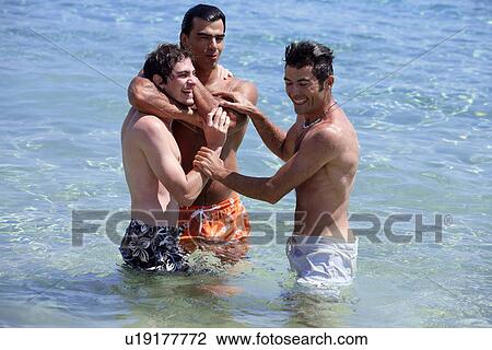 Stock Image - Three young men playing in the water. Fotosearch