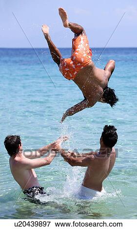 Stock Photo - Three young men playing in the water. Fotosearch