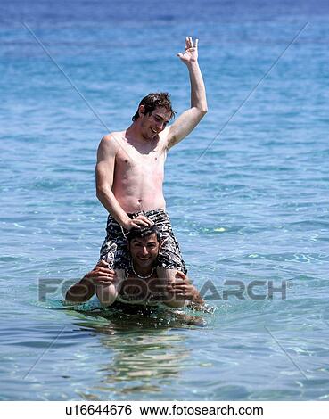 Stock Photograph - Two young men playing in the water. Fotosearch