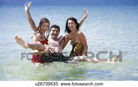 Stock Image - Young people playing around in the water. Fotosearch