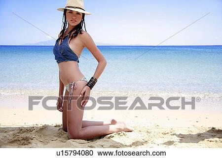 Young woman in hat kneeling on the beach View Large Photo Image Stock Image - Young woman in hat kneeling on the beach. Fotosearch
