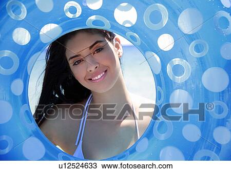 Stock Image - Young woman's face framed by inflatable life ring. Fotosearch