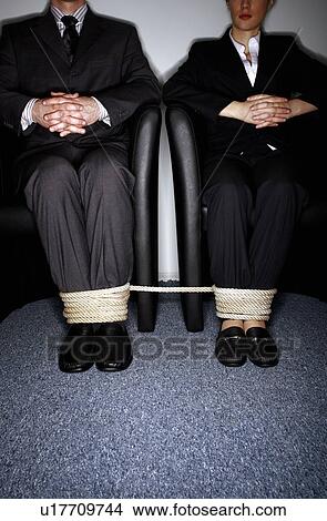 Picture - Male and female business people's legs tied. Fotosearch