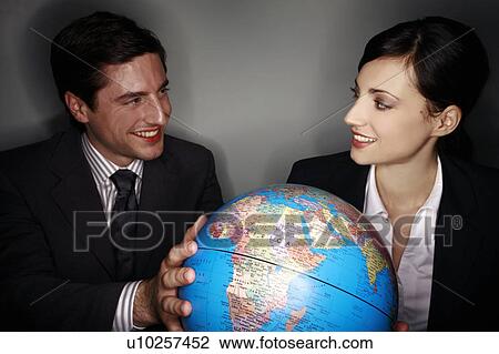 Stock Image - Male and female businesspeople with globe. Fotosearch