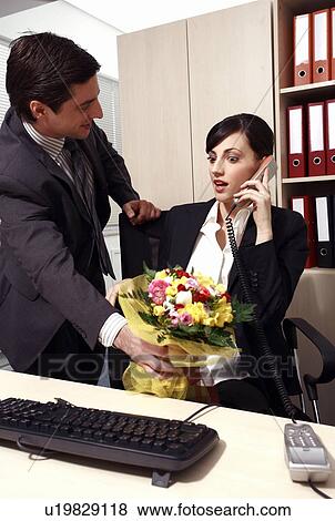 Stock Photo - Male office worker giving flowers to female colleague. Fotosearch