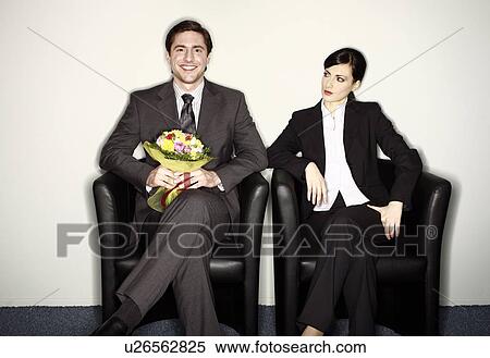 Stock Photography - Male office worker with flowers sitting next to female colleague. Fotosearch