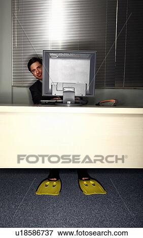 Stock Photo - Office worker at computer wearing swim flippers. Fotosearch