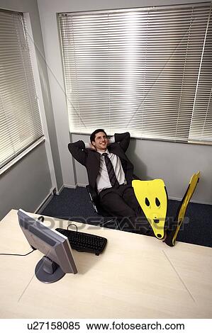 Stock Photography - Office worker at computer wearing swim flippers. Fotosearch