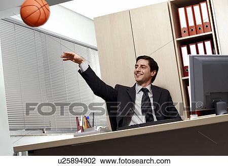 Office worker at desk playing with a basketball View Large Photo Image Stock Image - Office worker at desk playing with a basketball. Fotosearch