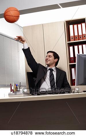Stock Photo - Office worker at desk playing with a basketball. Fotosearch