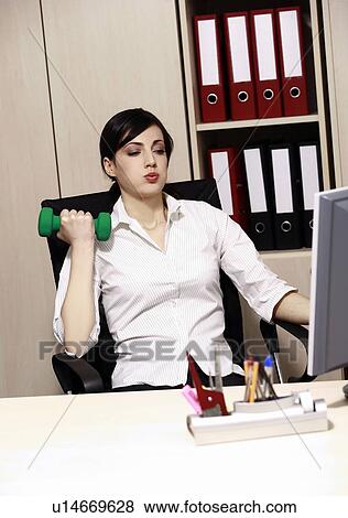 Stock Photo - Office worker at desk weight lifting. Fotosearch