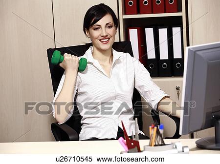 Stock Photography - Office worker at desk weight lifting. Fotosearch