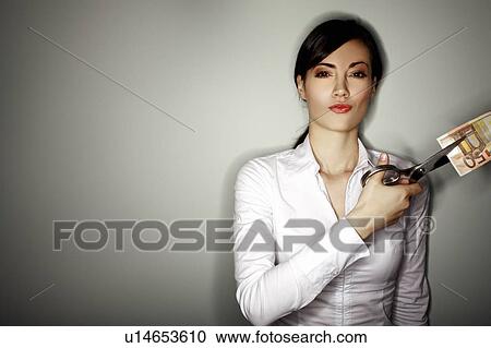 Stock Image - Office worker cutting a 50 euro bill. Fotosearch