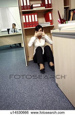 Office Worker On The Floor Covering Her Mouth Stock Photograph