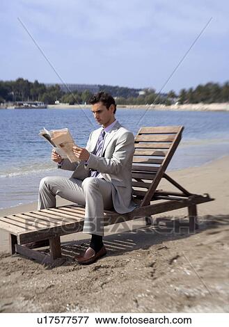 Businessman on beach with a newspaper View Large Photo Image Stock Photo - Businessman on beach with a newspaper. Fotosearch